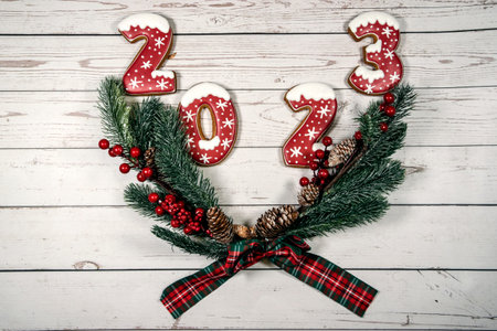 Christmas wreath with the numbers 2023 on a white wooden background. The concept of Christmas and...