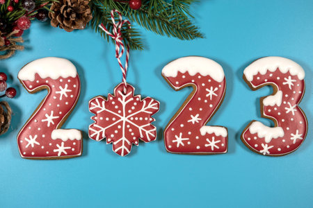 The inscription of gingerbread 2023 on a blue background with Christmas toys and a fir branch. A blank for a New Year's card. copyspace.の写真素材