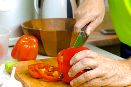 Men's hands are cutting red pepper for salad on a cutting board. close-up shooting. food photography.の写真素材