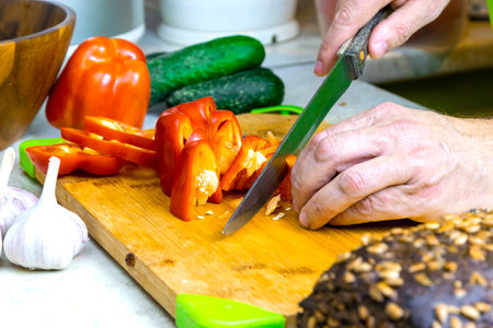 Men's hands are cutting red pepper for salad on a cutting board. close-up shooting. food photography.の写真素材