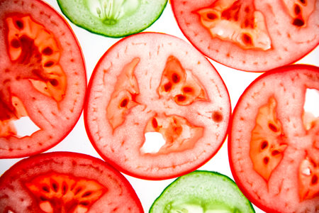 Slices of sliced tomatoes and cucumbers, taken to the light. The concept of healthy and healthy vegetables.の写真素材