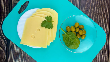 Sliced slices of fresh cheese on a plate with olives on wooden boards. The concept of home gastronomy.の写真素材