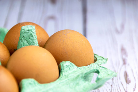 Red chicken eggs in a green tray on a wooden table. The concept of natural farm products.の写真素材