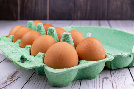 Red chicken eggs in a green tray on a wooden table. The concept of natural farm products.の写真素材