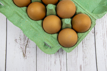Red chicken eggs in a green tray on a wooden table. The concept of natural farm products.の写真素材