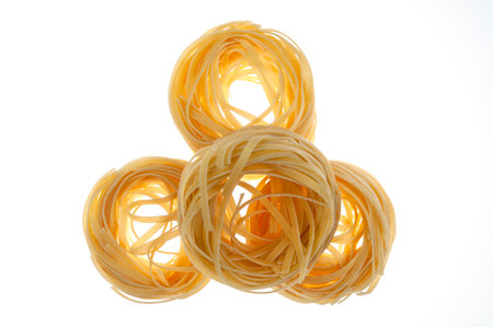 Nests of raw pasta on a white background. The concept of Italian cuisine.の写真素材
