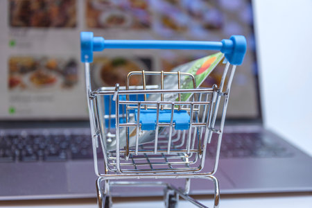 A supermarket cart with a credit card on the background of a laptop screen with an image of an...