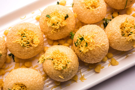 Stuffed Sev Puri is a popular Indian roadside chat item, served in a white plate. Top view,...