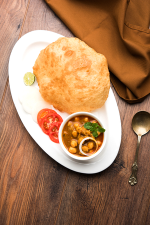 Chole Bhature or Chick pea curry and Fried  Puri served in terracotta crockery over white background. selective focusの写真素材