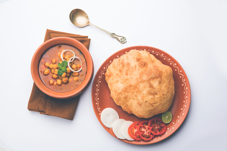 Chole Bhature or Chick pea curry and Fried  Puri served in terracotta crockery over white background. selective focusの写真素材
