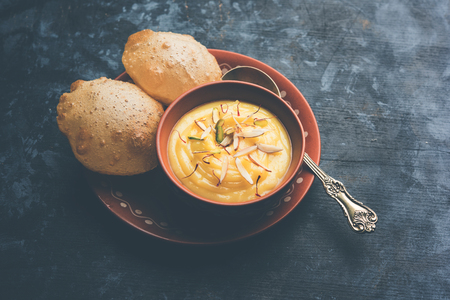 Shrikhand with fried Puri / Poori served in a bowl and plate over moody background. Selective focusの写真素材