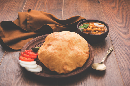 Chole Bhature or Chick pea curry and Fried  Puri served in terracotta crockery over white background. selective focusの写真素材