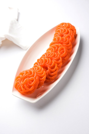 Indian sweet Imarti or Jalebi served in white ceramic plate over white backgroundの写真素材