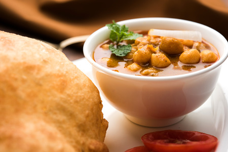 Chole Bhature or Chick pea curry and Fried  Puri served in terracotta crockery over white background. selective focusの写真素材