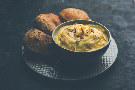 Shrikhand with fried Puri / Poori served in a bowl and plate over moody background. Selective focusの写真素材