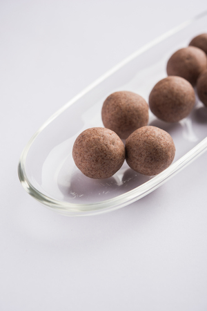 Nachni laddu or Ragi laddoo or balls made using  finger millet, sugar and ghee. It's a healthy food from India. Served in a bowl or plate over moody background. Selective focusの写真素材