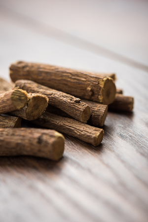 Ayurvedic Mulethi or Liquorice root stick or jeshthamadh powder served in a bowl over moody backgroundの写真素材