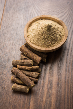 Ayurvedic Mulethi or Liquorice root stick or jeshthamadh powder served in a bowl over moody backgroundの写真素材