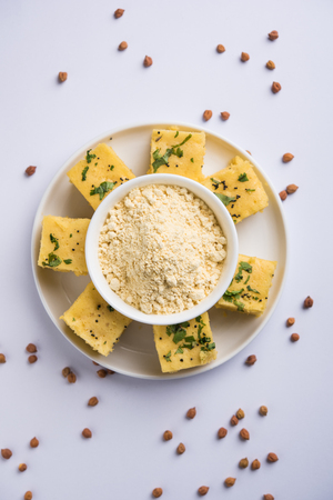 Chick pea flour or Besan powder in a ceramic or wooden bowl along with Gujrati Dhokla snackの写真素材