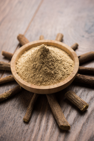 Ayurvedic Mulethi or Liquorice root stick or jeshthamadh powder served in a bowl over moody backgroundの写真素材