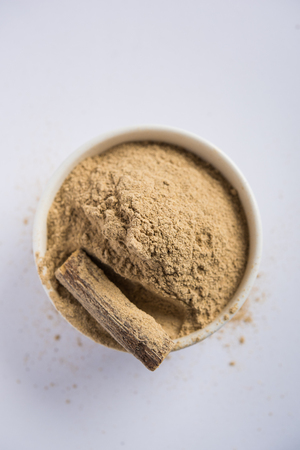 Ayurvedic Mulethi or Liquorice root stick or jeshthamadh powder served in a bowl over moody backgroundの写真素材