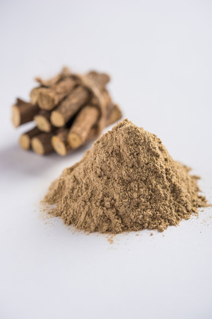 Ayurvedic Mulethi or Liquorice root stick or jeshthamadh powder served in a bowl over moody backgroundの写真素材