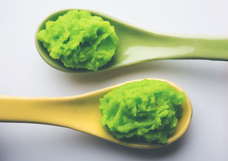 Green wasabi sauce or paste in bowl, with chopsticks or spoon over plain colourful background. selective focusの写真素材