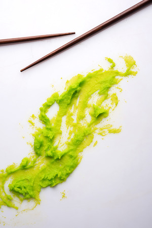 Green wasabi sauce or paste in bowl, with chopsticks or spoon over plain colourful background. selective focusの写真素材