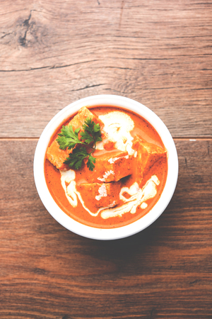 Paneer Butter Masala also known as Panir  makhani or makhanwala. served in a ceramic or terracotta bowl with fresh cream and coriander. Isolated over colourful moody background. selective focusの写真素材