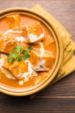 Paneer Butter Masala also known as Panir  makhani or makhanwala. served in a ceramic or terracotta bowl with fresh cream and coriander. Isolated over colourful moody background. selective focusの写真素材