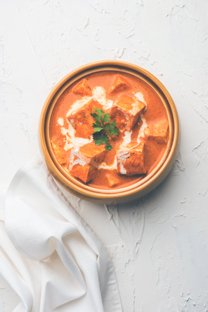 Paneer Butter Masala also known as Panir  makhani or makhanwala. served in a ceramic or terracotta bowl with fresh cream and coriander. Isolated over colourful moody background. selective focusの写真素材