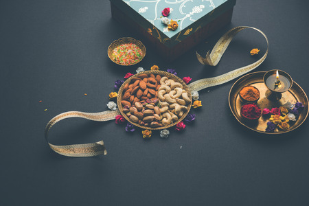 Raksha bandhan Festival greetings: conceptual Rakhi made using a plate full dry fruits like Cashew, pistachio, almond with fancy band and pooja Thali. selective focusの写真素材
