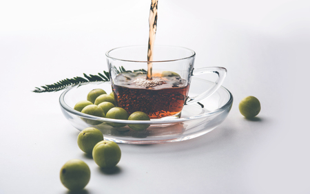 pouring amla Tea or Avla Chai in transparent glass cup with saucer over white or black background. Popular Ayurvedic medicine from Indiaの写真素材