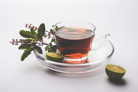 pouring Holy Basil or Tulsi Tea in transparent glass cup with saucer over white or black background. Popular Ayurvedic medicine from Indiaの写真素材