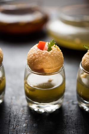 Pani Puri is an indian road side chat item - 4 stuffed puris kept over small glasses filled with mint waterの写真素材