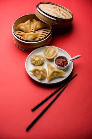 Dumpling momos food from Nepal or Ladakh served with red chilli chutney over moody background. Selective focusの写真素材