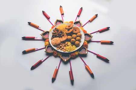Rangoli or design made using Diya/oil lamp with Indian snacks/sweet and firecrackers or patakhe for Diwali festivalの写真素材