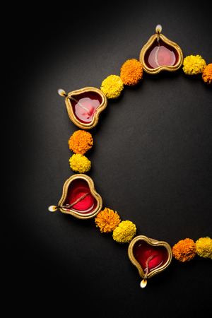 Diwali glowing Diya and flowers arranged in circular shape forming a designの写真素材