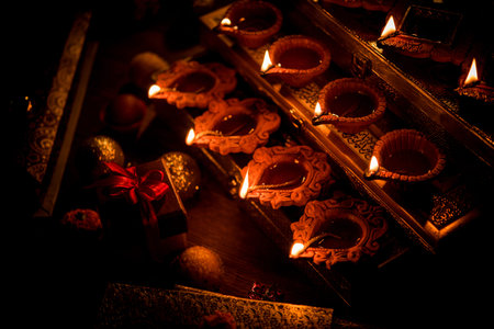 Diwali diya or lighting in the night with gifts, flowers over moody background. Selective focus