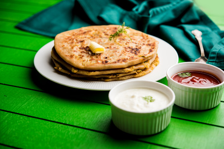 Aloo Paratha / Indian Potato stuffed Flatbread. Served with fresh curd and tomato ketchup. selective focusの写真素材