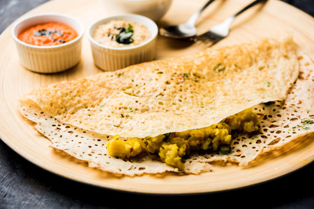Onion rava masala dosa is a South Indian instant breakfast served with chutney and sambar over moody...