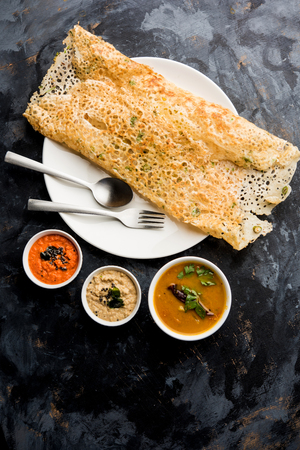 Onion rava masala dosa is a South Indian instant breakfast served with chutney and sambar over moody background. selective focusの写真素材
