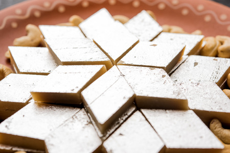 Kaju Katli is a Diamond shape Indian sweet made using cashew sugar and mava, served in a plate or bowl over moody background. selective focusの写真素材