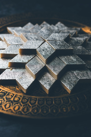 Kaju Katli is a Diamond shape Indian sweet made using cashew sugar and mava, served in a plate or bowl over moody background. selective focusの写真素材