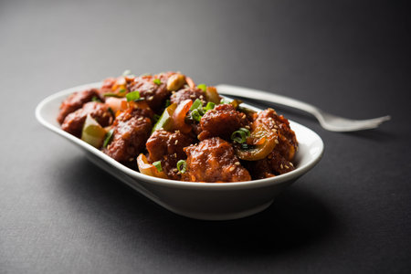 Indian Chilli Chicken dry, served in a plate over moody background. Selective focus