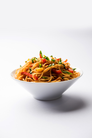 Schezwan Noodles or vegetable Hakka Noodles or chow mein is a popular Indo-Chinese recipes, served in a bowl or plate with wooden chopsticks. selective focusの写真素材
