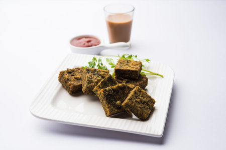 A savory cilantro cake or kothimbir vadi in square shape which is first steamed and then fried until...