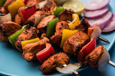 Chicken tikka /skew Kebab. Traditional Indian dish cooked on charcoal and flame, seasoned & colourfully garnished. served with green chutney and salad. selective focusの写真素材