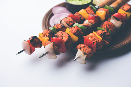 Chicken tikka /skew Kebab. Traditional Indian dish cooked on charcoal and flame, seasoned & colourfully garnished. served with green chutney and salad. selective focusの写真素材