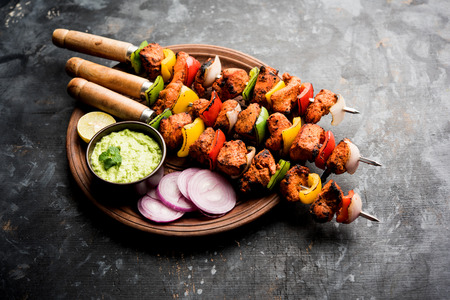 Chicken tikka /skew Kebab. Traditional Indian dish cooked on charcoal and flame, seasoned & colourfully garnished. served with green chutney and salad. selective focusの写真素材